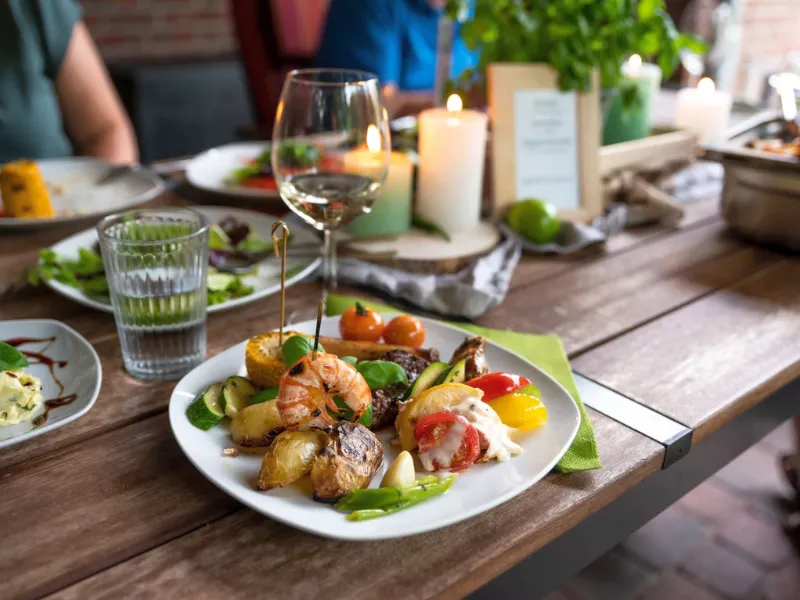 Privatkoch grillt Fleisch und Beilagen vor Ort, gedeckter Tisch